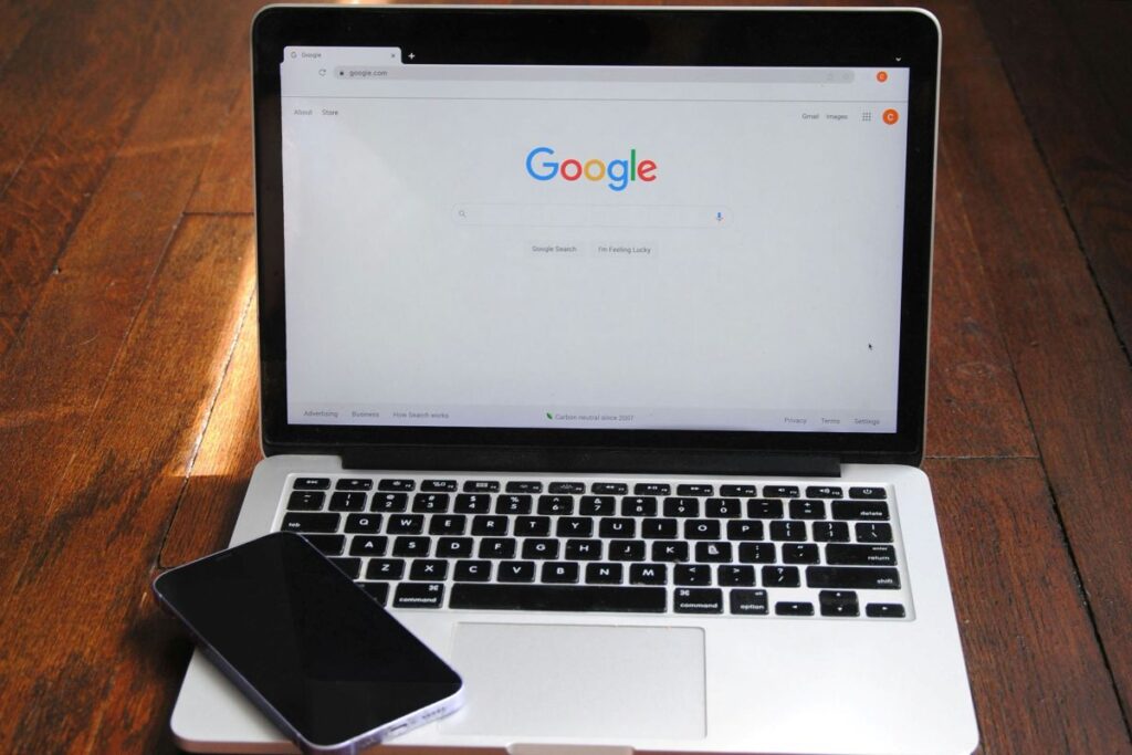 Foto Google: Laptop con homepage Google e smartphone — articolo su AEO e Intelligenza Artificiale per studi dentistici